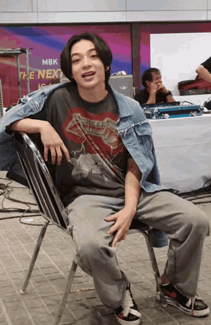 a man wearing a metallica shirt sits in a chair