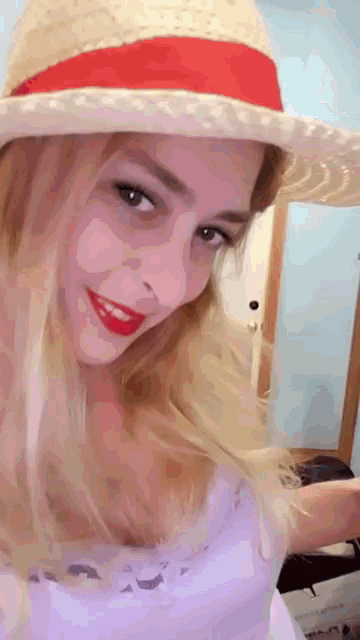 a woman wearing a straw hat with a red ribbon is smiling