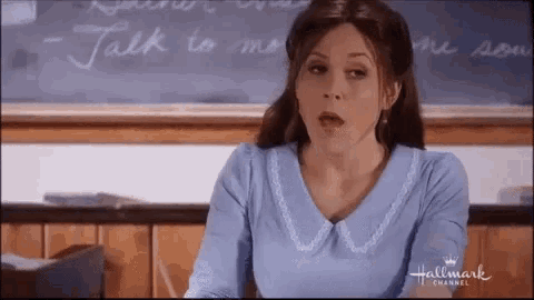 a woman is sitting in front of a blackboard in a classroom .