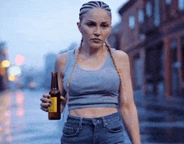 a woman in a blue tank top is holding a beer