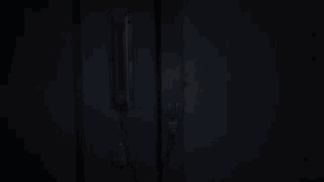a person is chained to a door in a dark room .