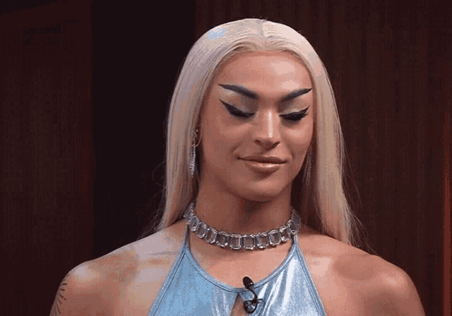 a woman wearing a blue top and a silver necklace with the letter s on it