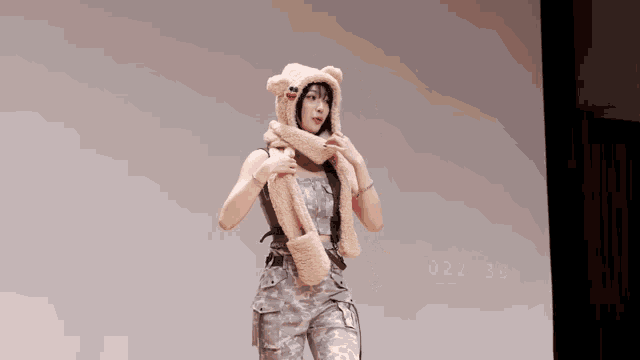 a woman wearing a teddy bear hat and scarf stands on a stage