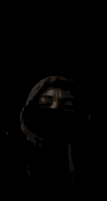 a person wearing a hooded jacket with their face covered in a black cloth .