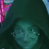 a close up of a person wearing glasses and a black hood .