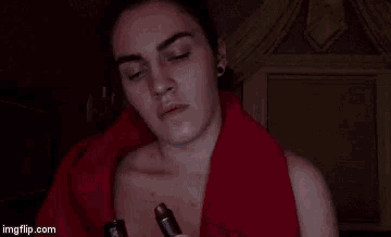 a woman wrapped in a red blanket is holding a lipstick .