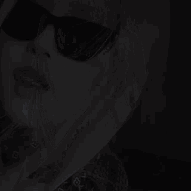 a close up of a woman 's face wearing sunglasses in the dark .