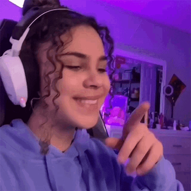 a girl wearing headphones is smiling while looking at her phone