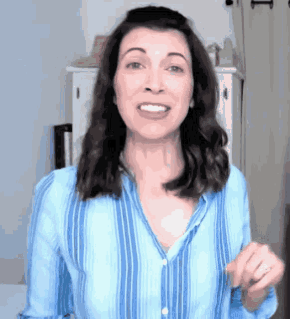 a woman in a blue striped shirt is smiling with her mouth open