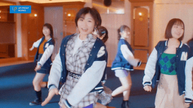 a group of girls are dancing in a room with a sign that says up front working