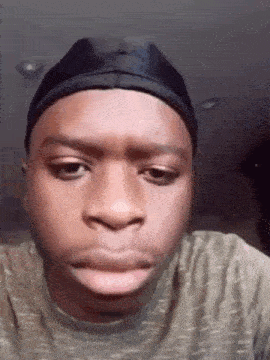 a young man wearing a black hat is making a funny face .