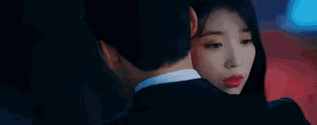 a man and a woman are hugging each other . the woman is wearing red lipstick .