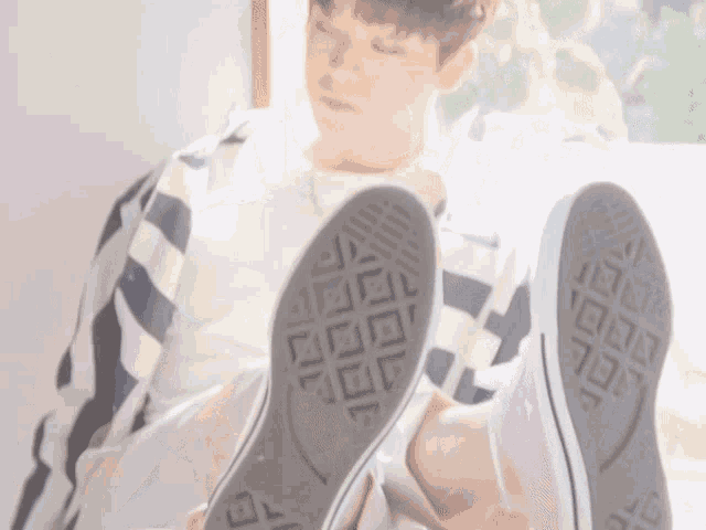 a person laying on the floor with their feet up and their converse shoes on