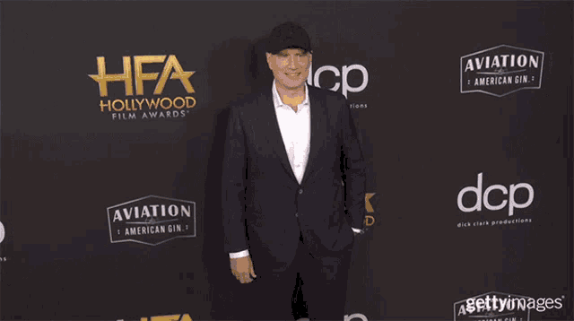 a man in a suit is standing in front of a hollywood film awards carpet