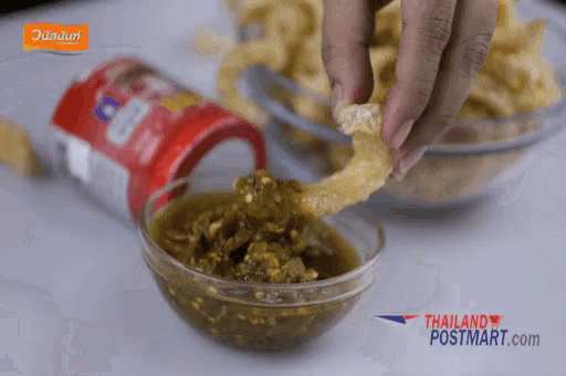 a person dipping a piece of food into a bowl of sauce with thailand postmart.com written on the bottom