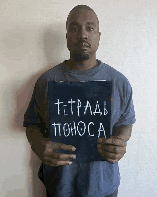 a man in a blue shirt holds up a sign that says tetpaab pomoca