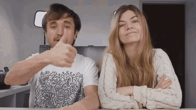a man giving a thumbs up next to a woman wearing a sweater