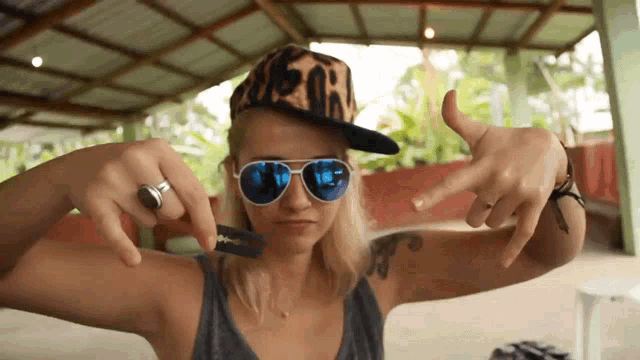 a woman wearing a leopard print hat and sunglasses is making a peace sign