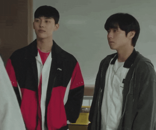 two young men standing next to each other with one wearing a jacket with the word asics on it