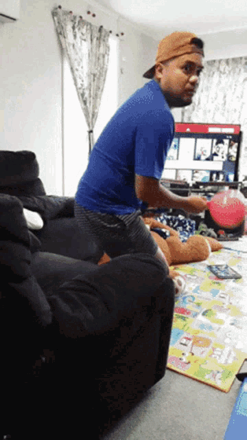 a man in a blue shirt is standing in front of a tv