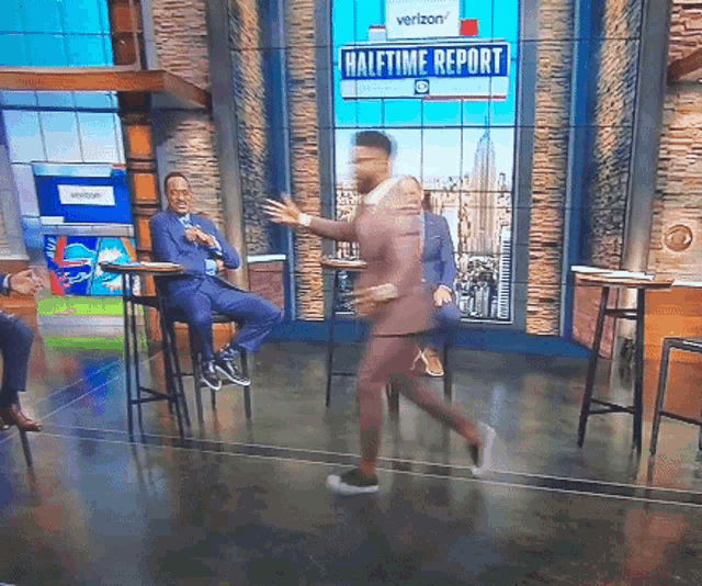 a man in a suit is walking in front of a halftime report sign