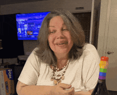 a woman sitting in front of a tv holding a bottle of wine with a pom box in the background
