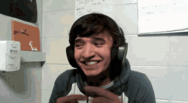 a man wearing headphones is smiling in front of a wall with a sign that says ' a ' on it