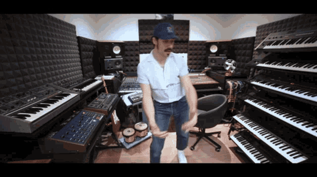 a man wearing a dodgers hat is dancing in a room filled with keyboards and drums