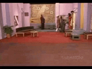 a group of people standing in a room with a couch and tables
