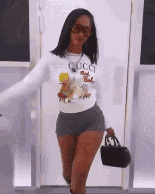 a woman wearing a gucci shirt and shorts is holding a black purse