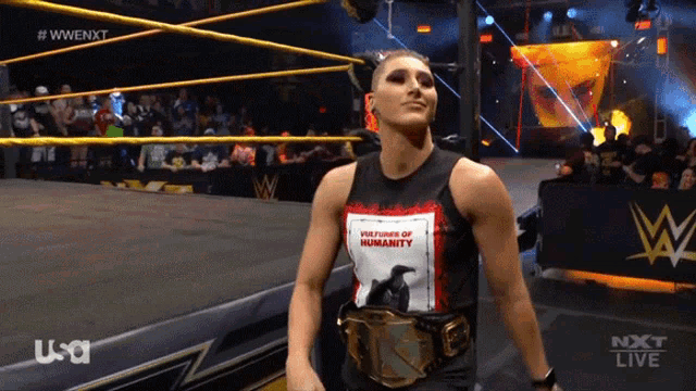 a woman in a wrestling ring wearing a shirt that says welcome to humanity