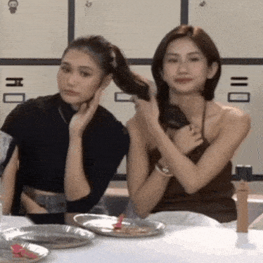 two women are sitting at a table with a plate of food in front of them