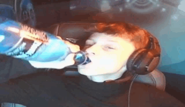 a young boy wearing headphones is drinking from a bottle of vodka .