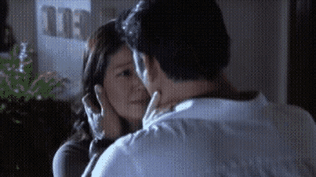 a man and a woman are kissing each other in a room .