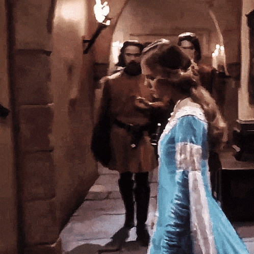 a woman in a blue dress stands in a hallway
