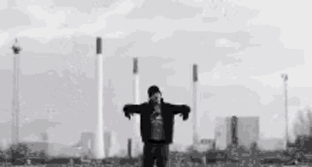 a black and white photo of a man standing in front of a large explosion .