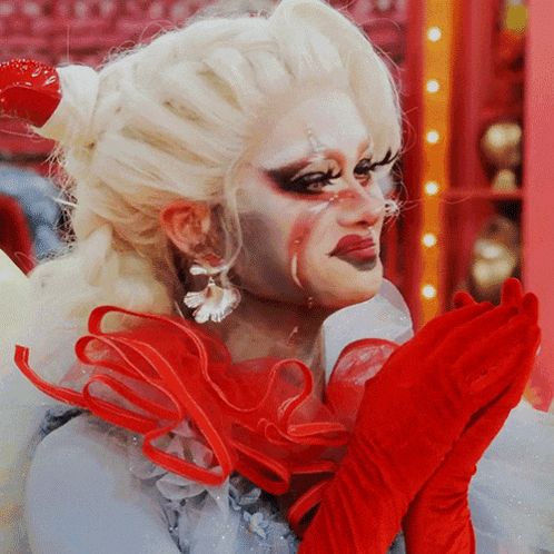 a drag queen wearing red gloves and a wig
