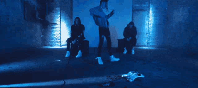 a group of people are dancing in a room with a blue light behind them