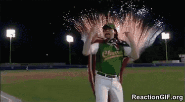 a baseball player is standing in front of a fireworks display .