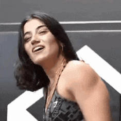 a woman is smiling and looking at the camera while wearing a black tank top .