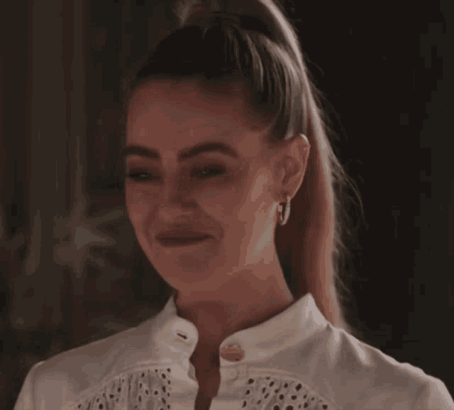 a woman wearing hoop earrings and a ponytail smiles