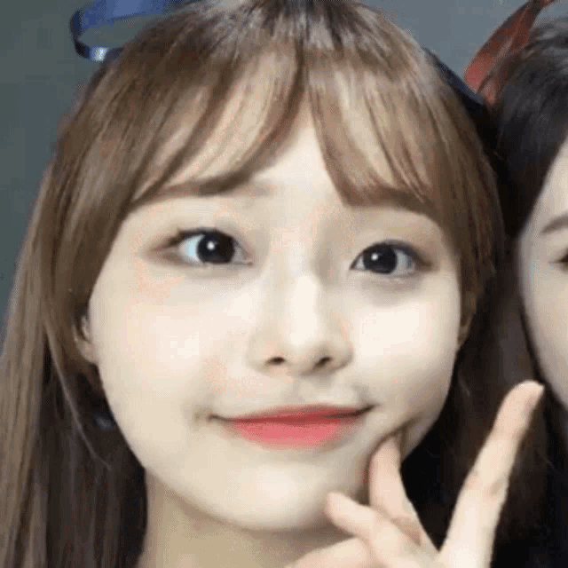 a close up of a girl making a peace sign with her fingers