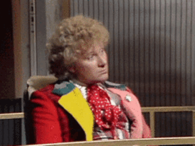 a man in a red jacket and yellow scarf is sitting on a bench