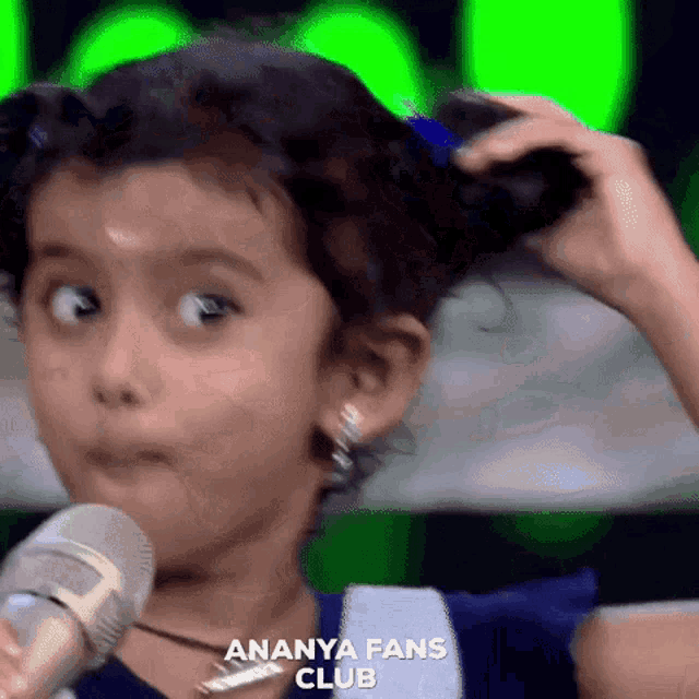 a little girl is holding a microphone and making a funny face