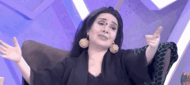 a woman is sitting in a chair with her arms outstretched and a purple background .
