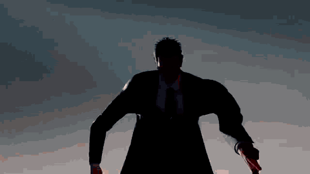 a silhouette of a man in a suit and tie is pointing up