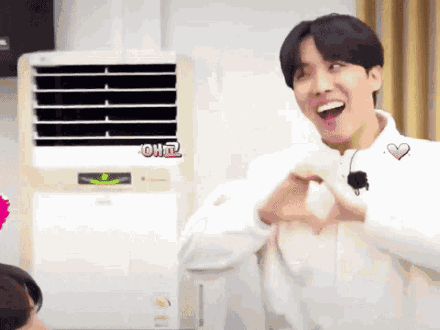 a man making a heart shape with his hands in front of a fan