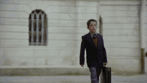 a man in a suit and tie is walking down a sidewalk carrying a briefcase