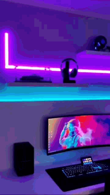 a computer is sitting on a desk in a room with purple lights on the walls .