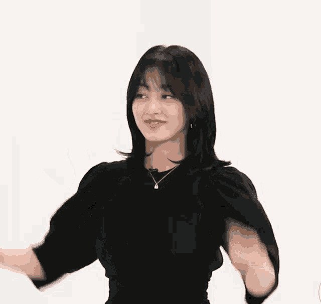 a woman wearing a black top and a necklace is holding her hair